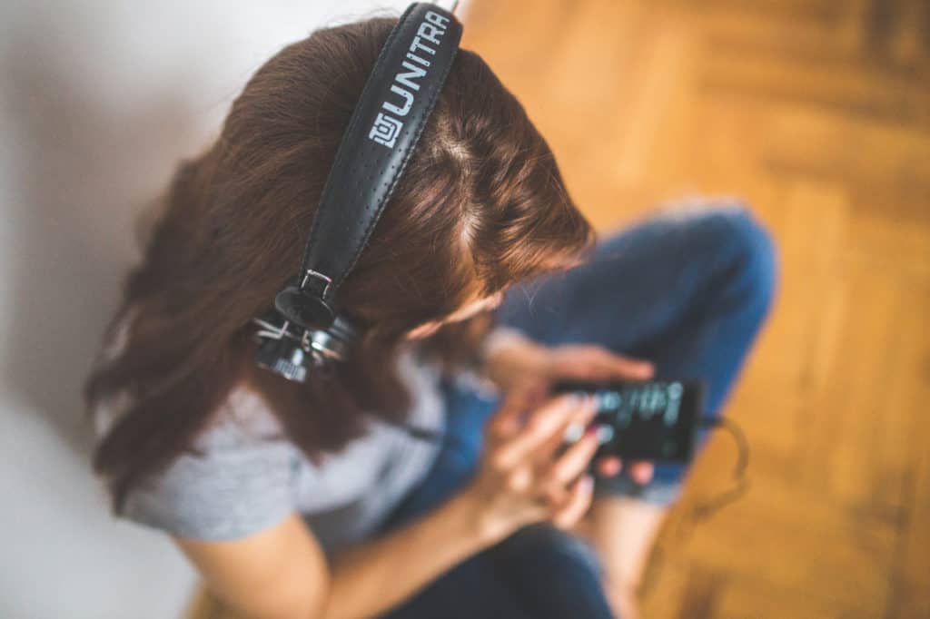 Kvinde med høretelefoner lytter til musik fra sin mobiltelefon